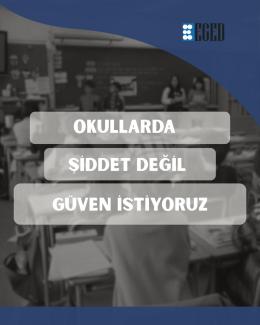 Bir sınıf ortamını gösteren siyah-beyaz fotoğrafın üzerine yerleştirilmiş yazılı bir afiş. Arka planda sıralar ve bir yazı tahtası bulunan sınıfta birkaç kişi silik şekilde görünüyor. Üst sağ köşede “EGED” yazan bir logo var; solunda 6 beyaz noktalı mavi bir simge bulunuyor. Ortada yarı saydam üç şerit içinde büyük beyaz metin yer alıyor.  OKULLARDA ŞİDDET DEĞİL GÜVEN İSTİYORUZ